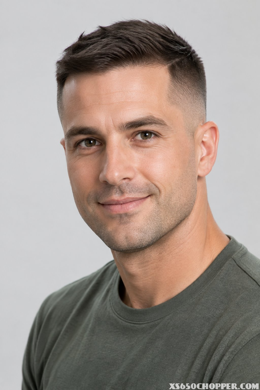 A man with a short textured high-and-tight haircut poses against a plain background.