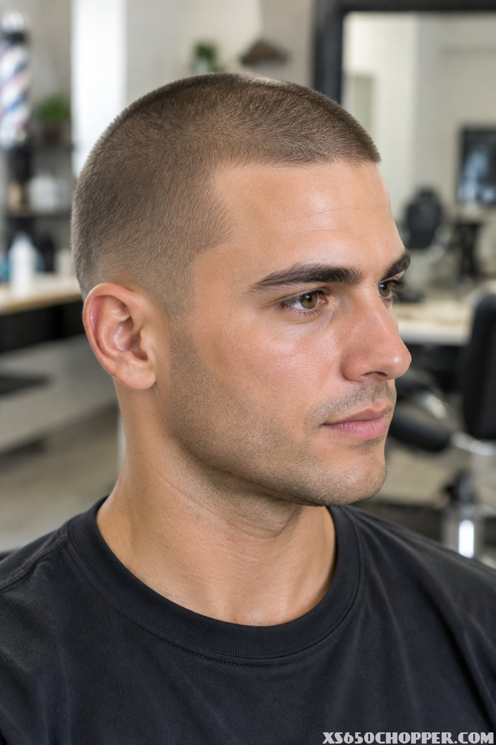 A man with an evenly clipped short buzz cut in a modern barbershop.
