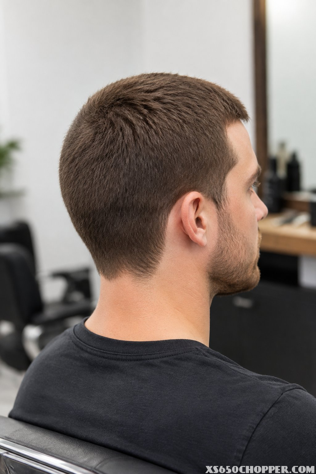 A man with a neat, evenly clipped short haircut sits in a modern barbershop.