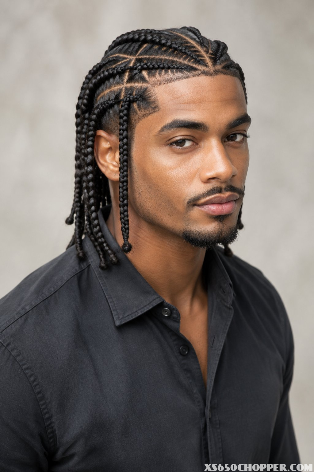 A confident man displays a neat braided hairstyle in a modern portrait.