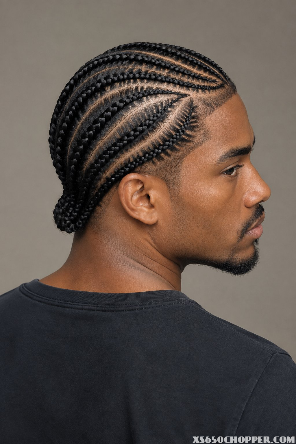 A man displays neatly braided cornrows arranged in curved rows across his scalp.