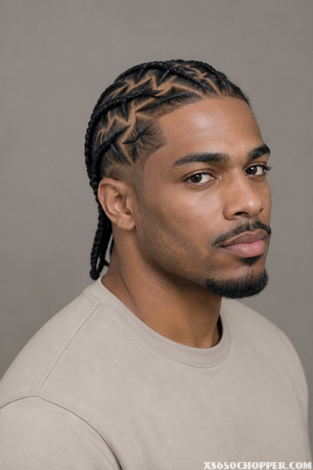 A man with neatly arranged zigzag stitch braids poses against a plain background.