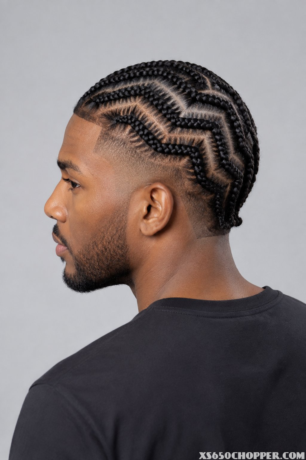 A man is shown from behind with zigzag cornrows and a faded haircut at the temples.