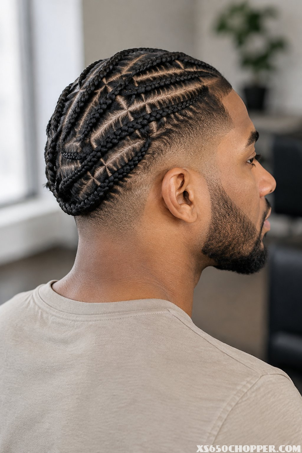 A man displays neatly patterned cornrows with a high taper fade.