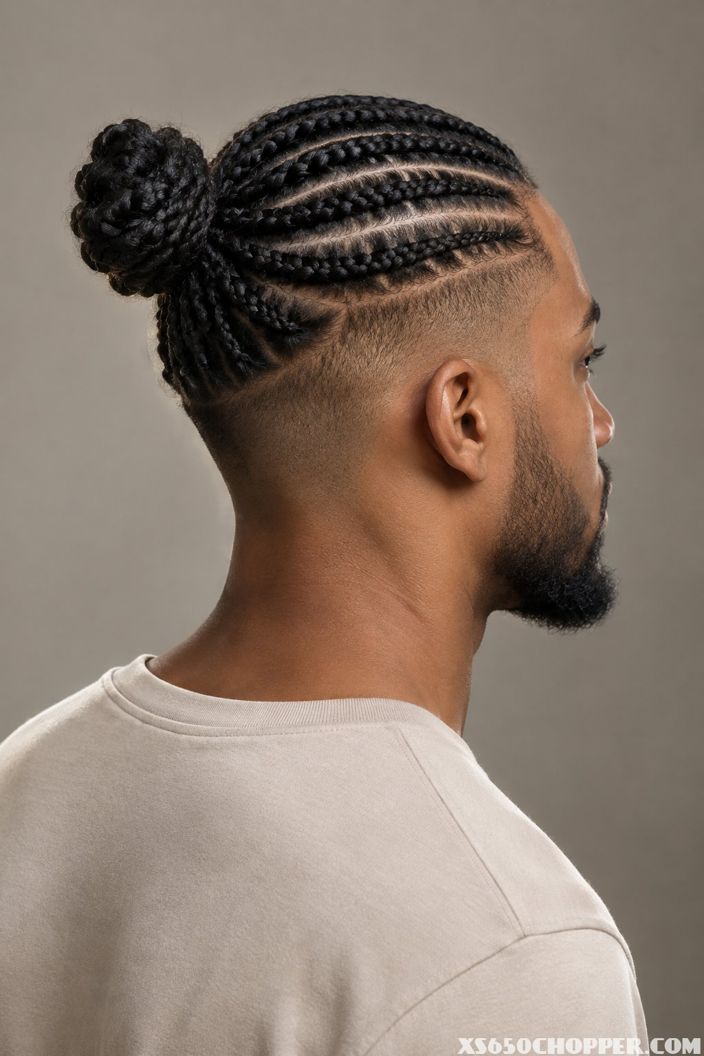 A man with cornrows gathered into a bun and a closely shaved undercut.