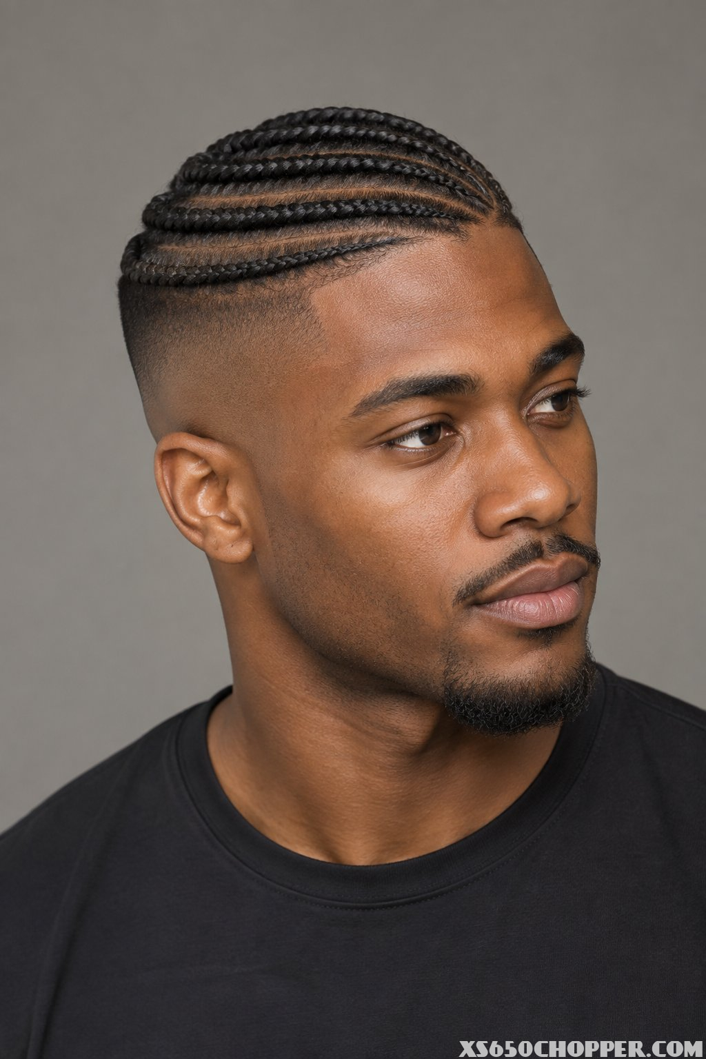 A man with side-swept cornrows and closely shaved sides.