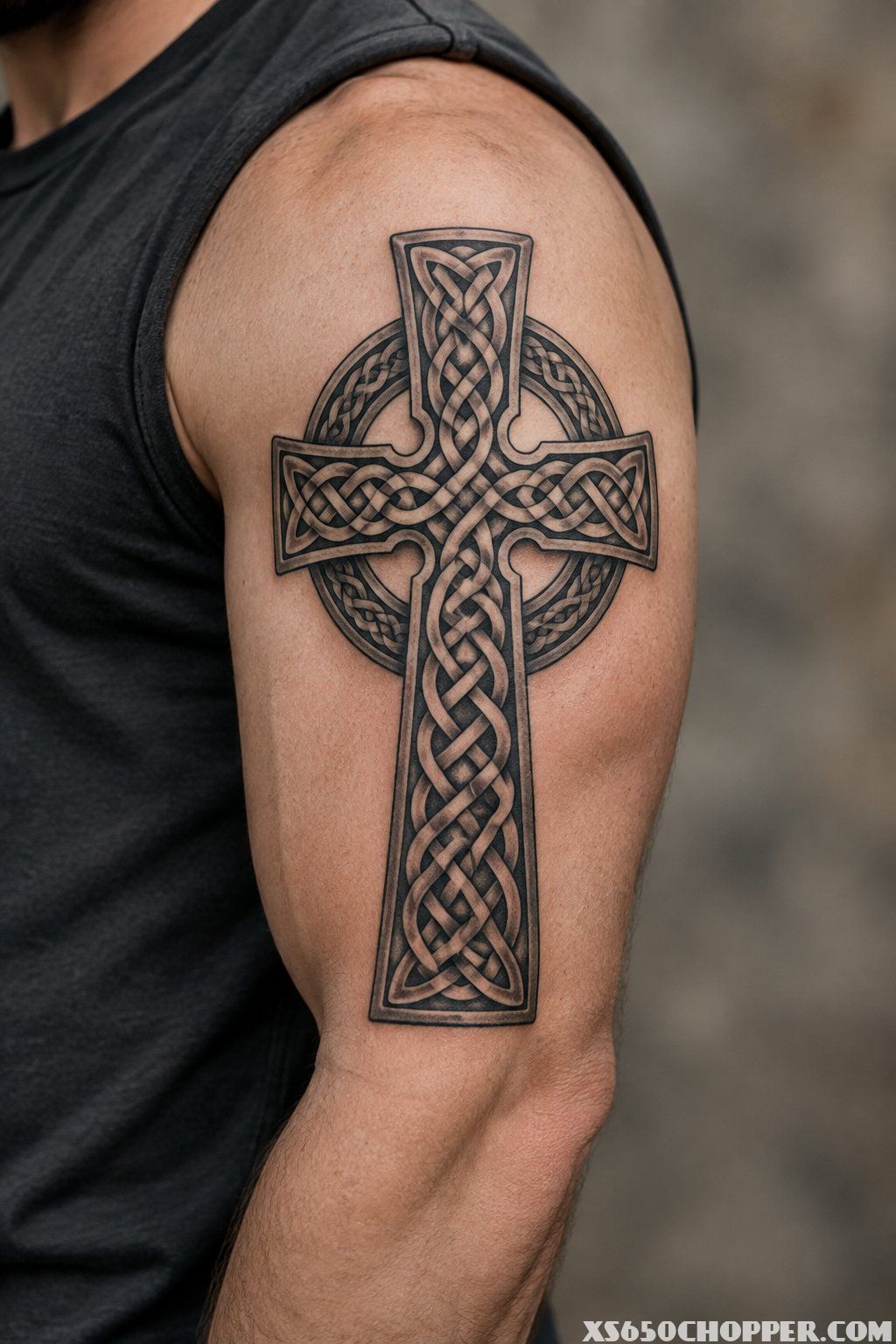 A Celtic cross tattoo with intricate knotwork on a man's upper arm.