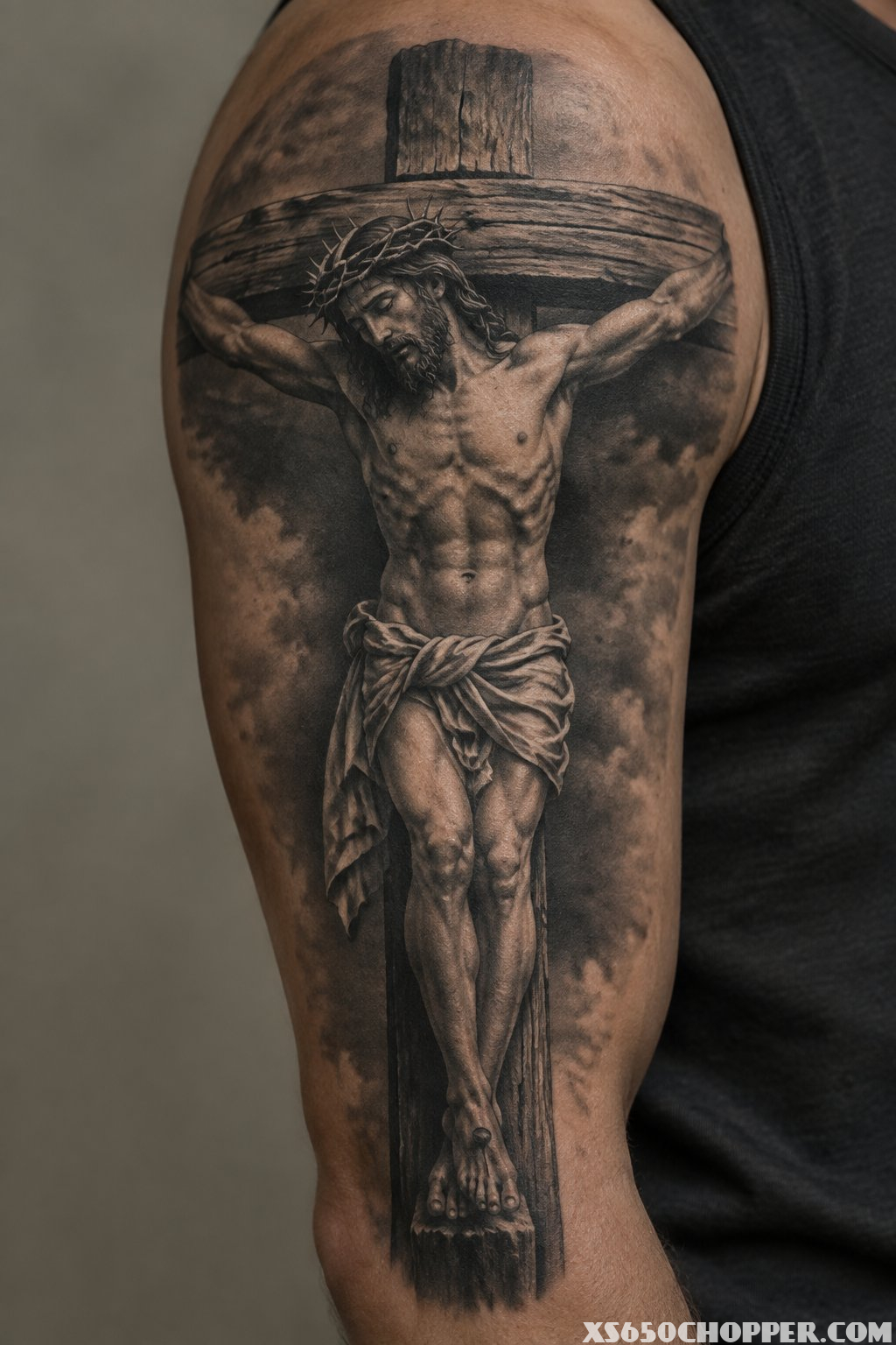 A detailed crucifix tattoo with a portrait of Jesus on a man's arm.
