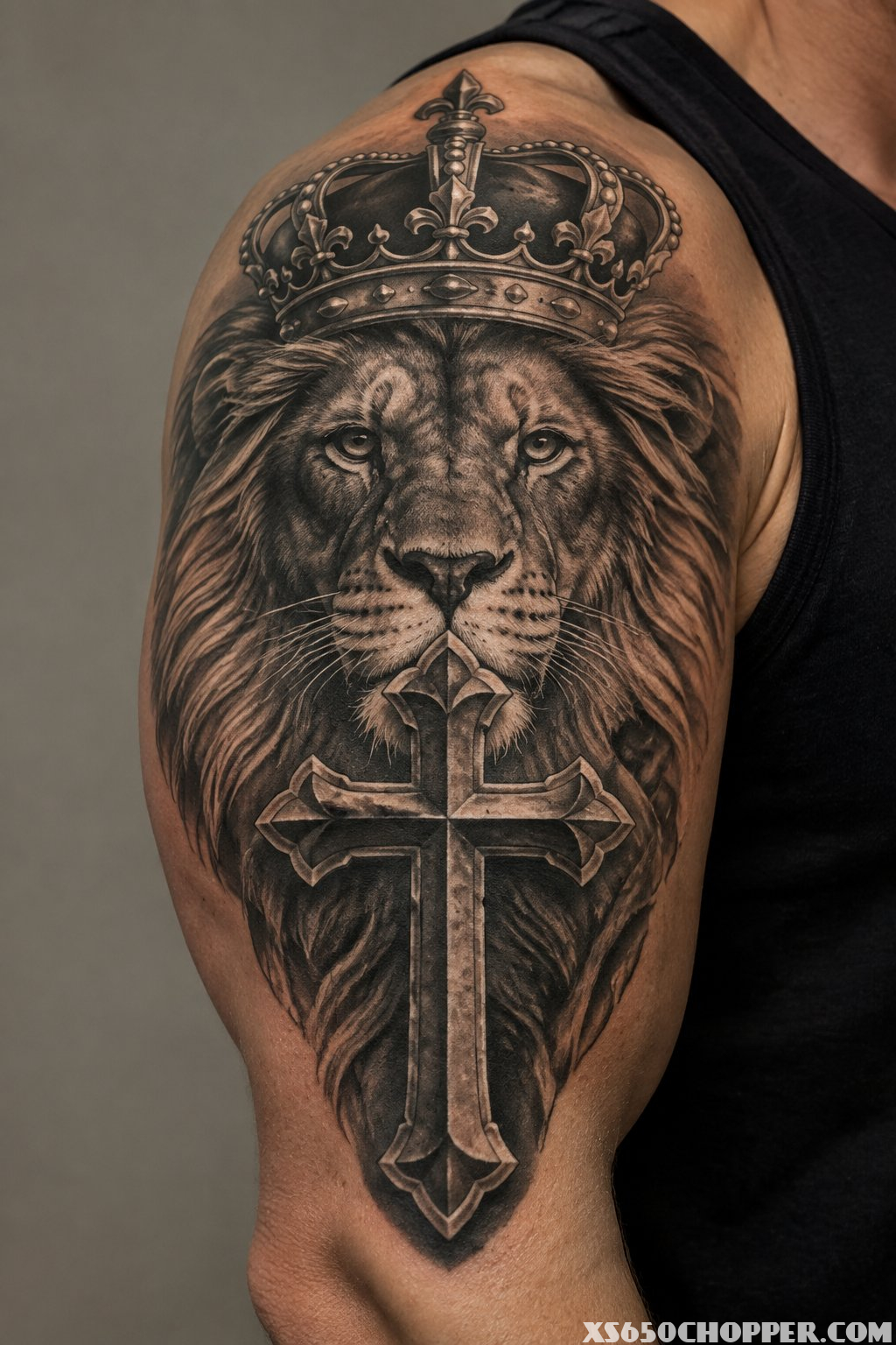 A detailed tattoo of a cross with a lion and crown on a person’s skin.