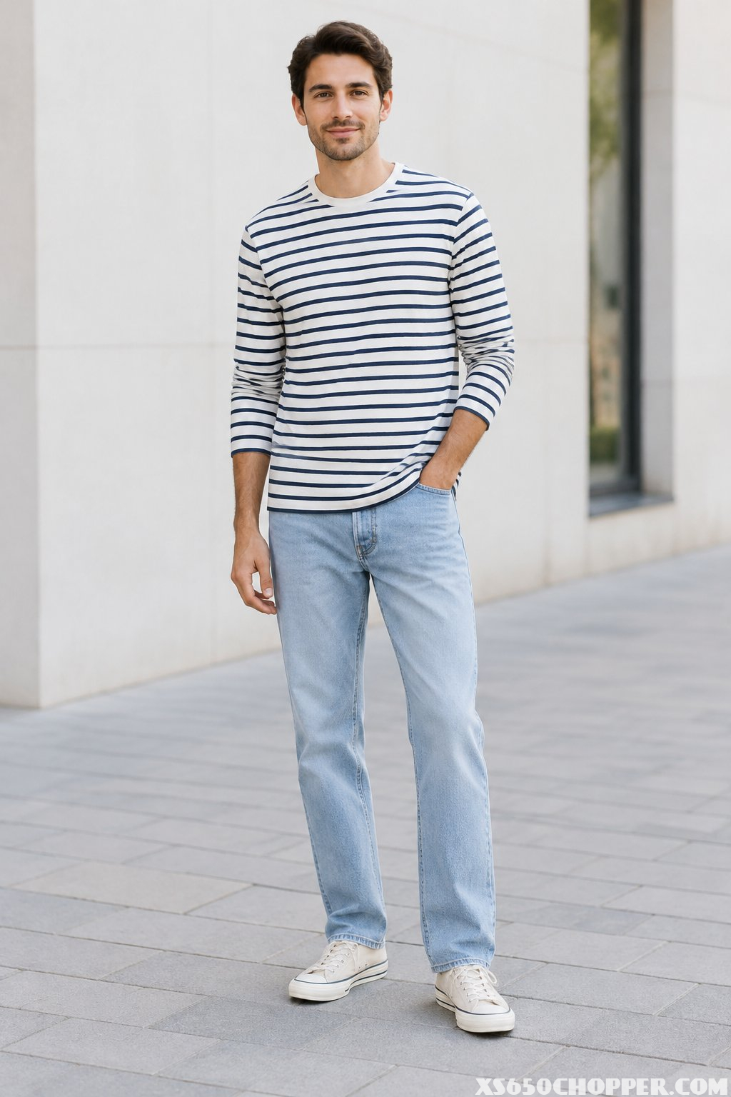 A man wearing a striped long-sleeve shirt, light-wash jeans, and canvas sneakers.