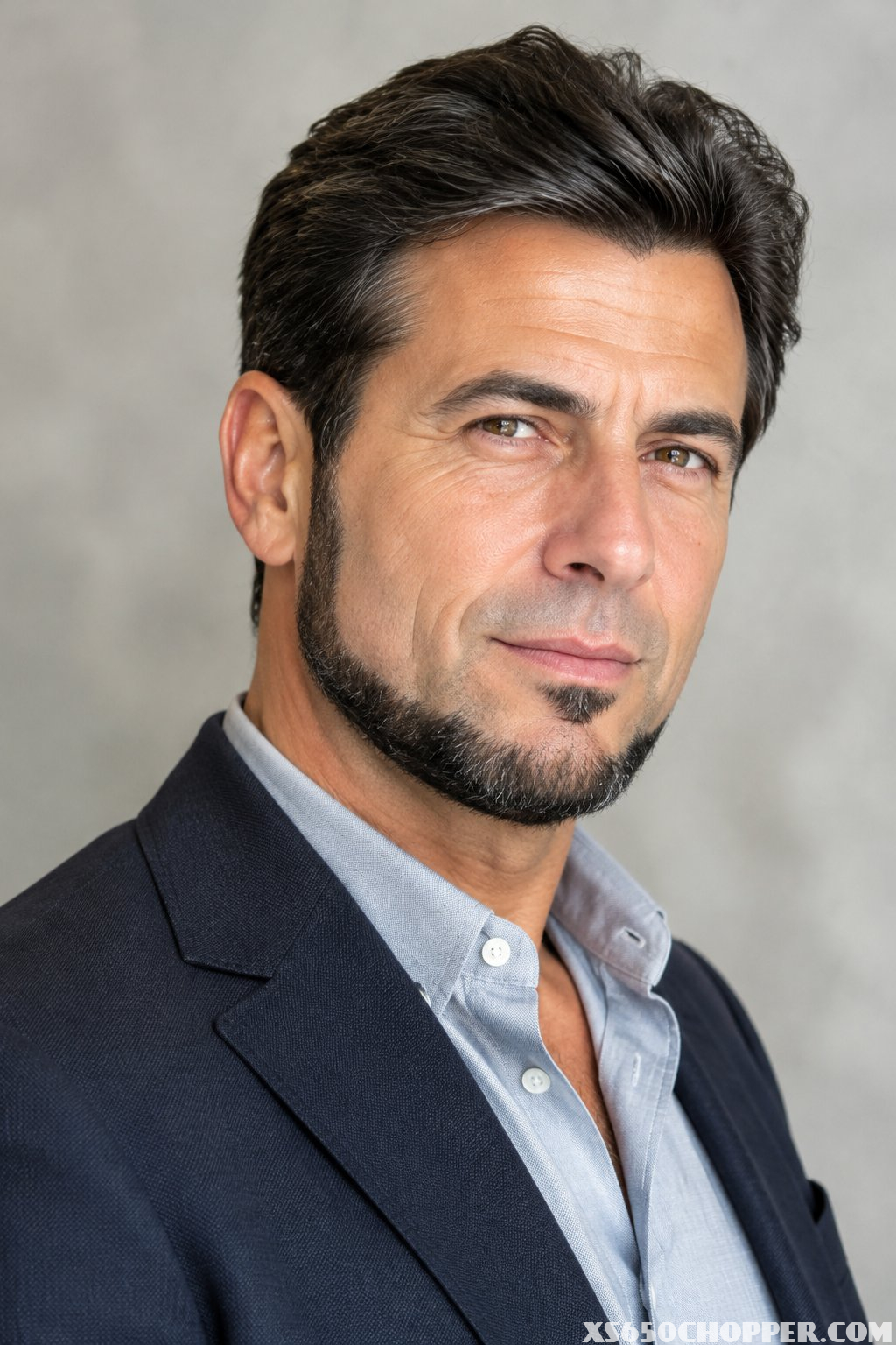 A man in his late 40s poses in a softly lit studio.