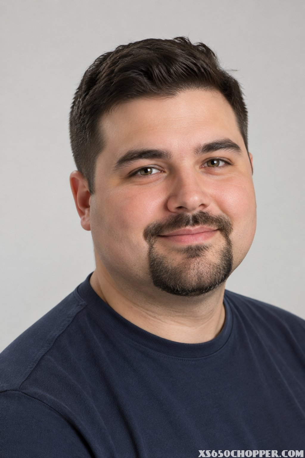 A man with a round face and a neatly trimmed short goatee.