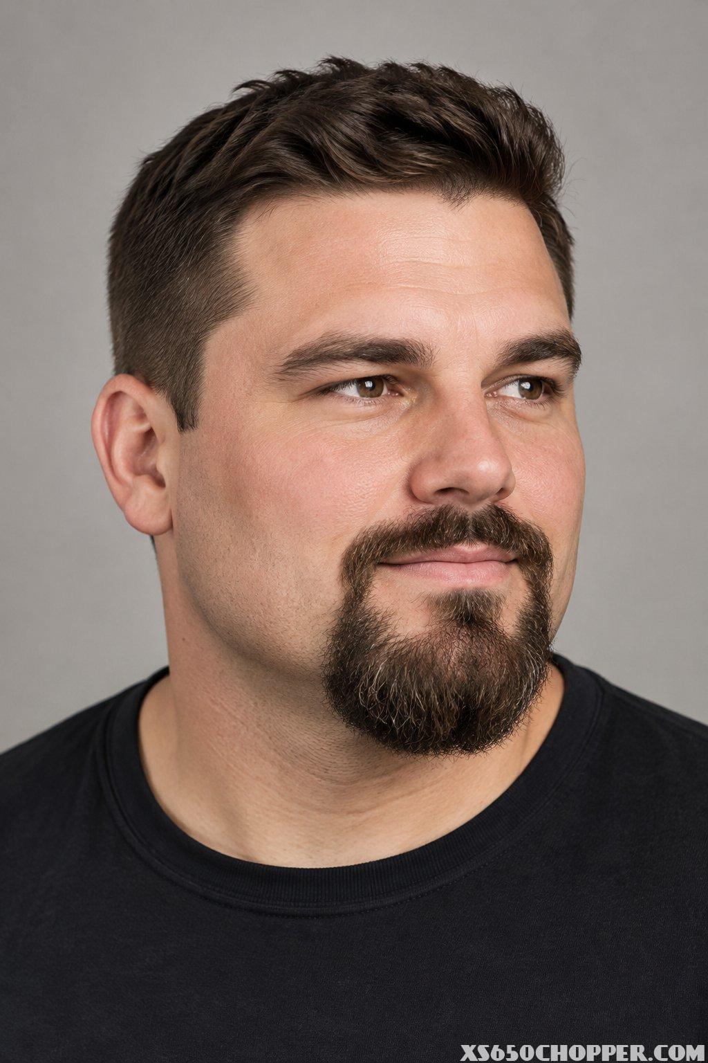 A man with a broad face and a neatly groomed extended goatee.
