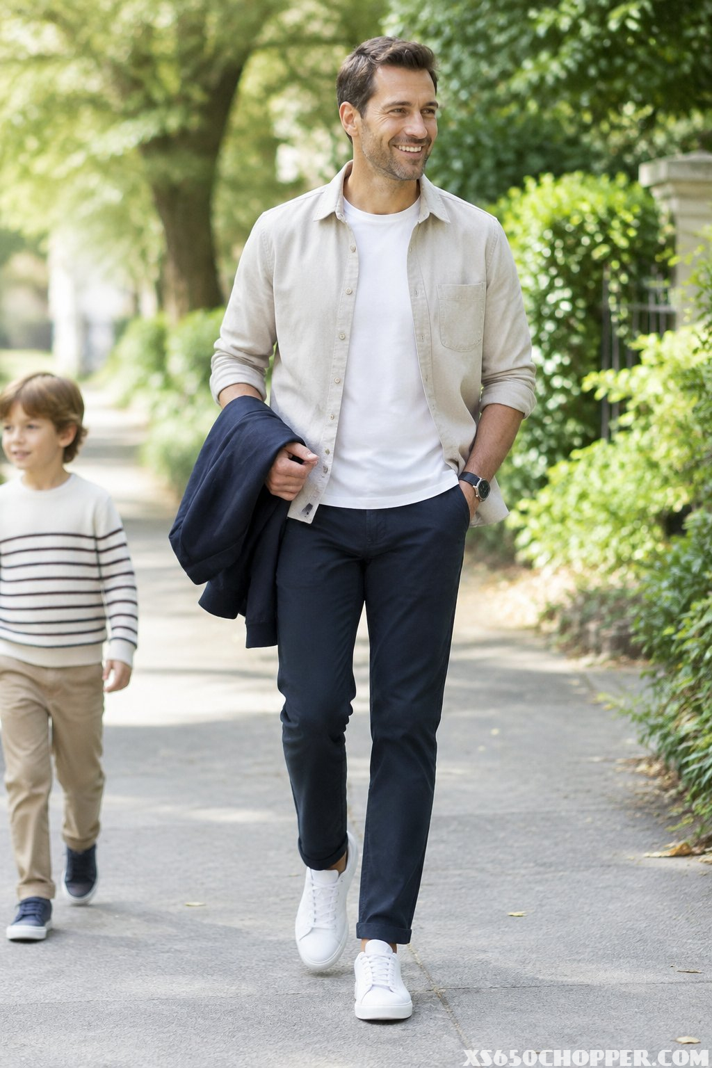 A father walks along a leafy path beside his child.