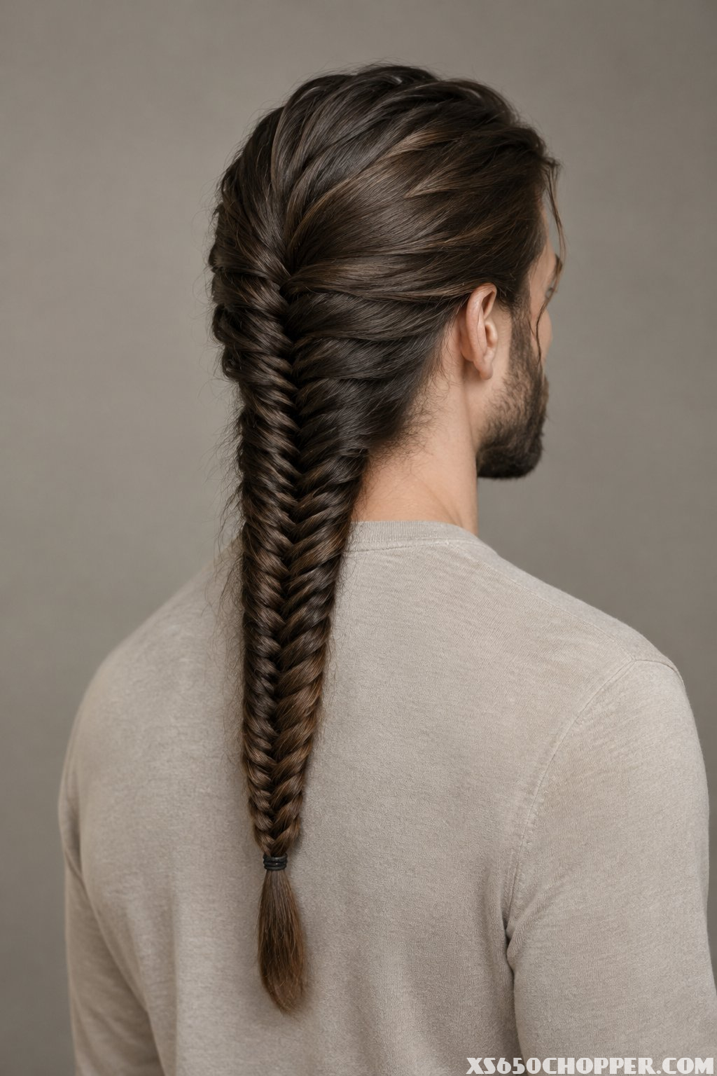 A man stands with his back partly turned in a softly lit studio.