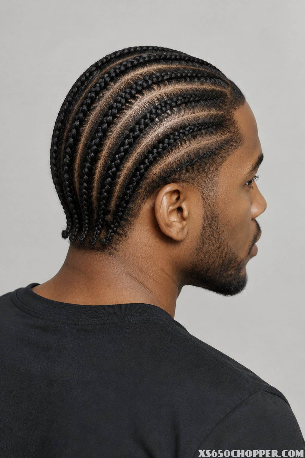 A man with short braided hair photographed from behind.