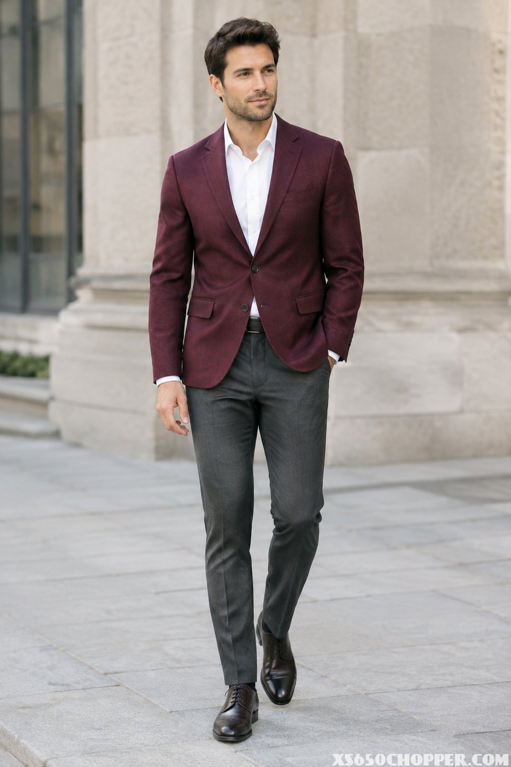 A man wearing a burgundy blazer and charcoal trousers.