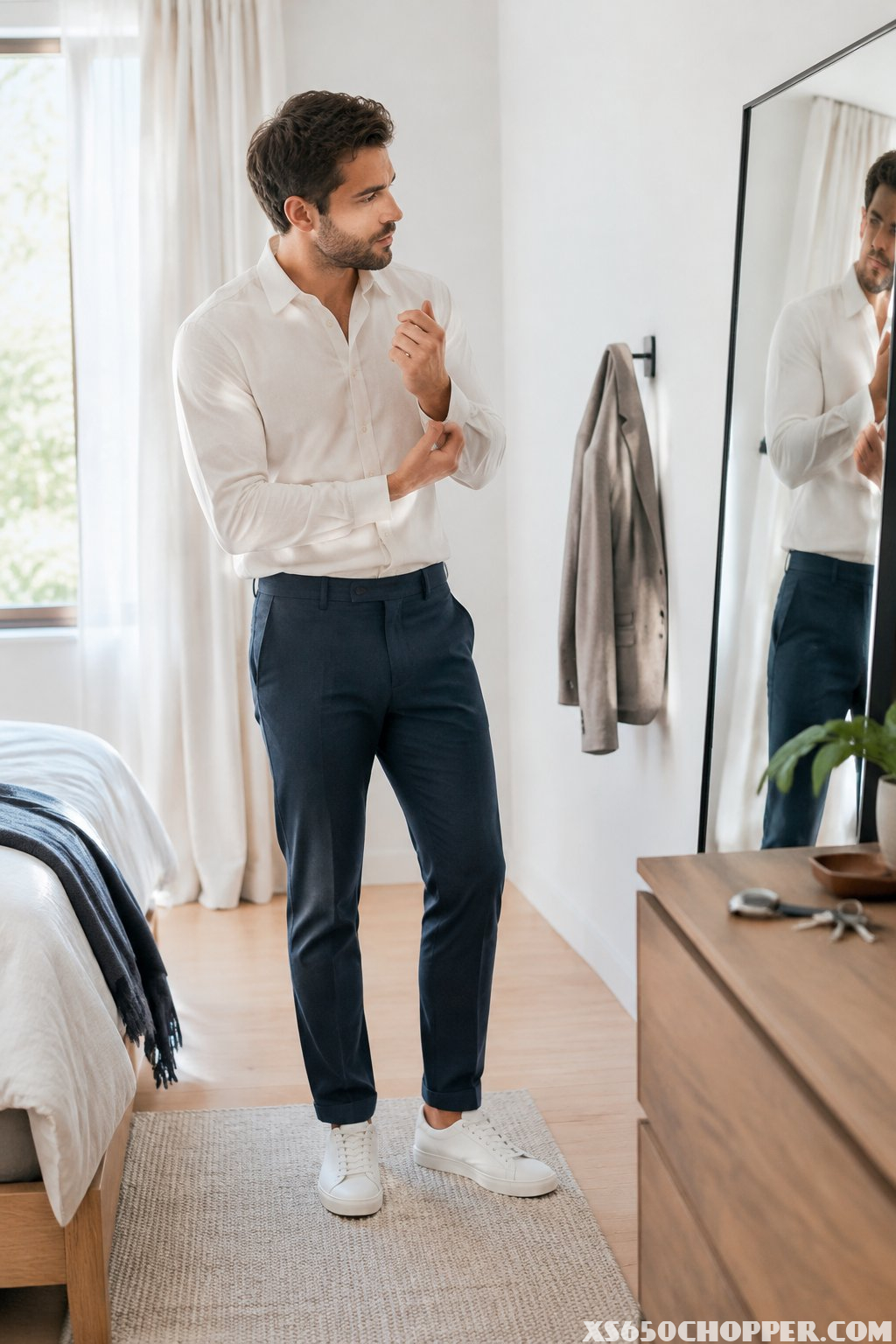 A man checks his outfit in a bedroom mirror before leaving.