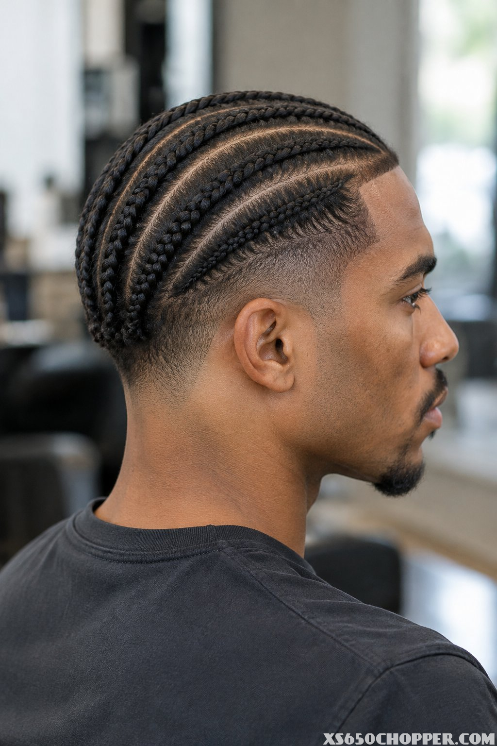 A man seated in a barbershop, shown from behind and in profile.