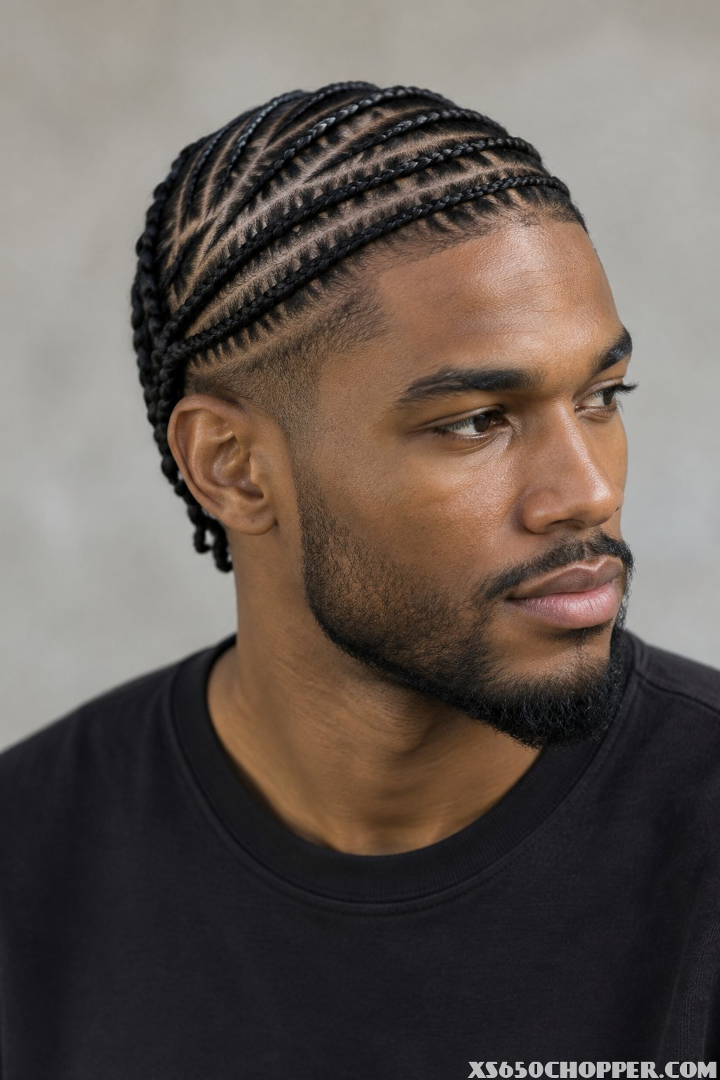 A man poses in a softly lit studio.