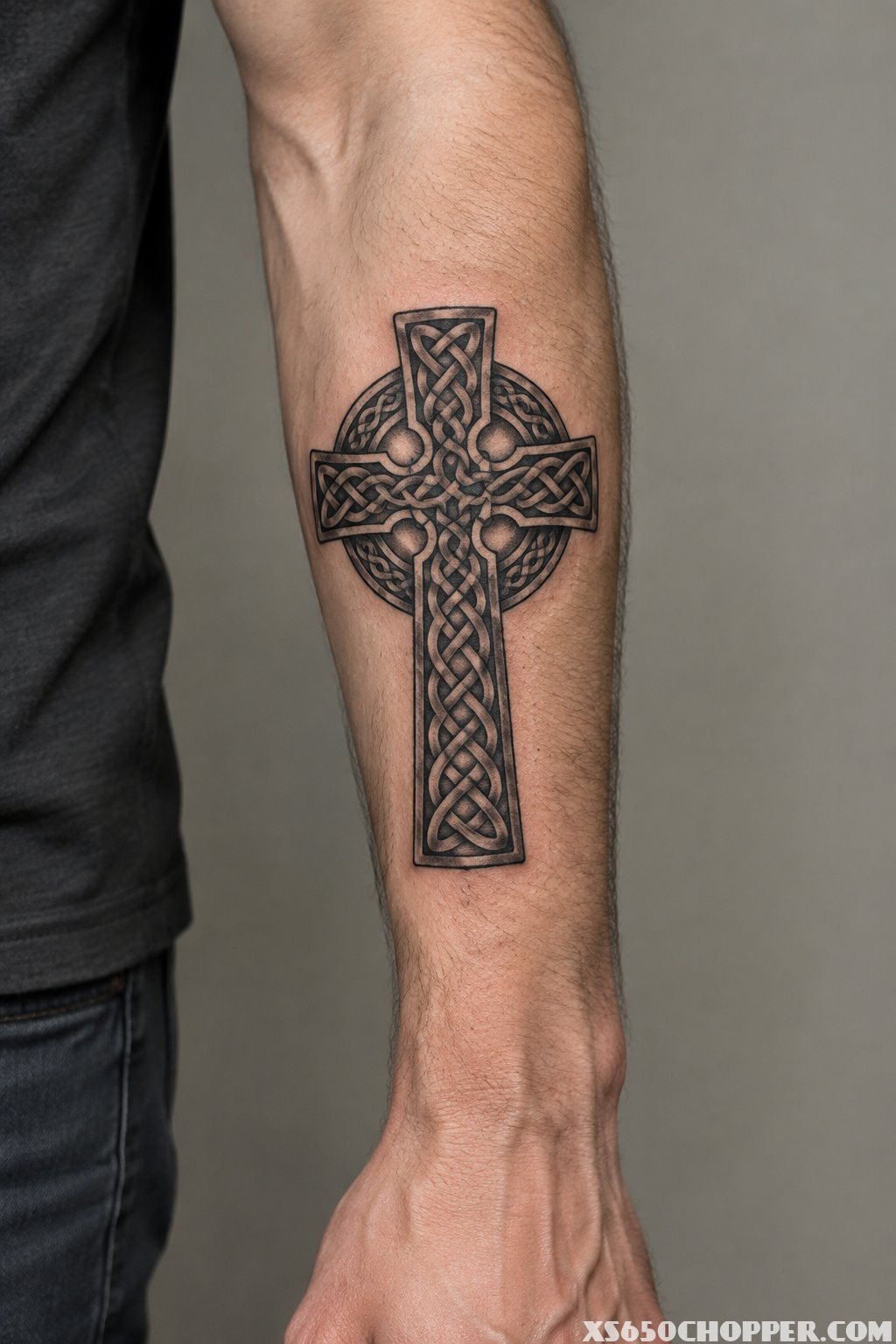 A man’s forearm displaying a Celtic knot cross tattoo.