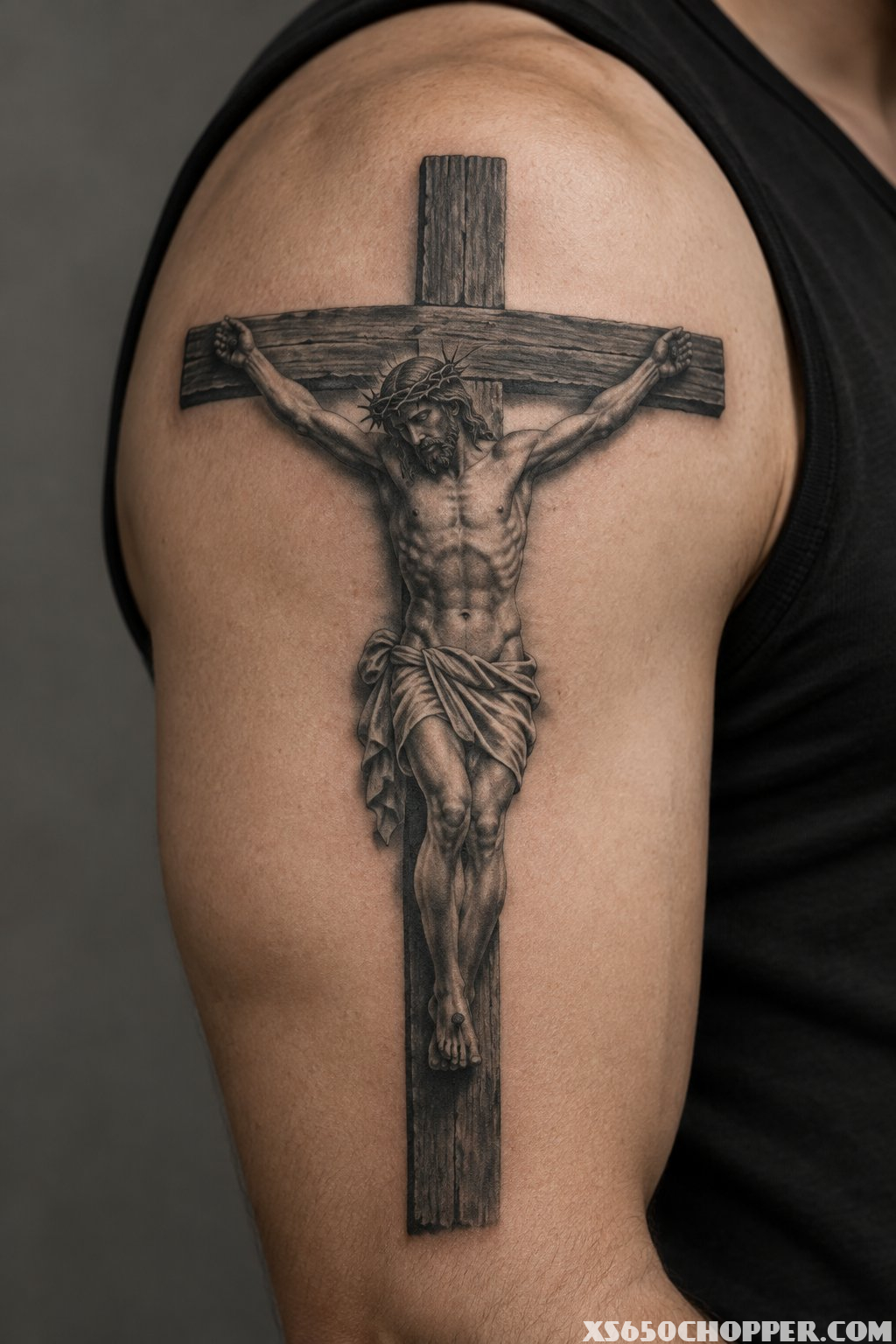 A detailed figure of Christ on a cross tattooed on a man's upper arm.