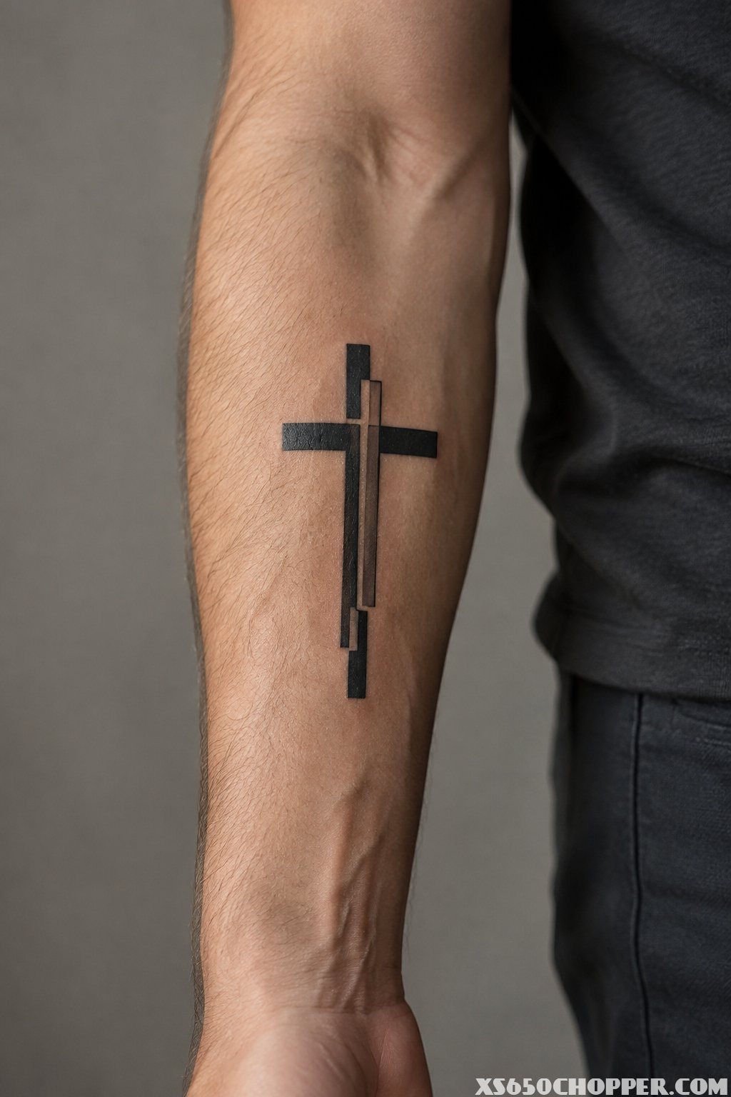 A geometric black cross tattoo on a man's forearm.