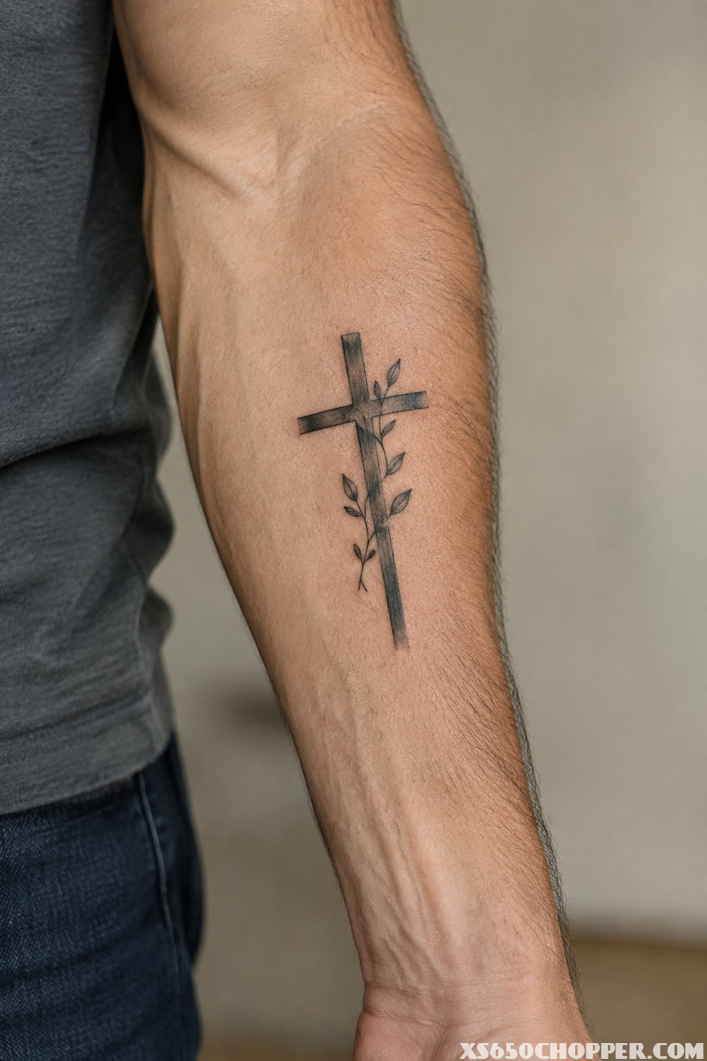 A man's forearm with a cross tattoo.