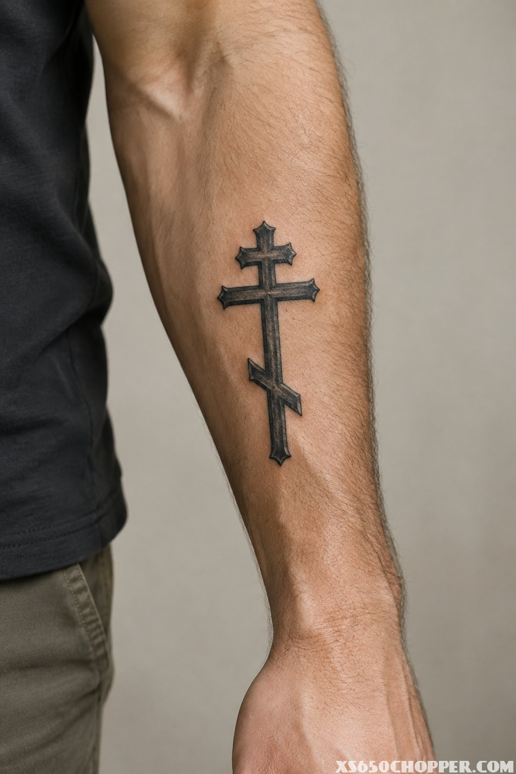 An Orthodox cross tattoo with three crossbars on a man’s forearm.